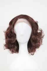 Natural looking dark brunet wig on white mannequin head. Middle length brown hair on the plastic...
