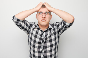 Portrait of angry young man screaming tearing hair out of head isolated on white studio background. Devil boss face. Human emotions, facial expression concept