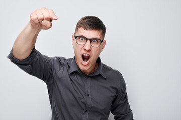 Portrait of angry young man yelling pointing menacingly at camera isolated on white studio background. Devil boss face. Human emotions, facial expression concept