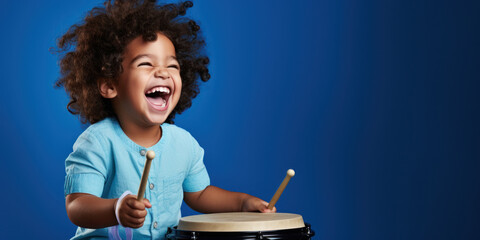 Hispanic boy, playing a toy drum, against a royal blue background, room for copyspace