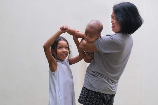 A mother playing with her daughter and baby boy