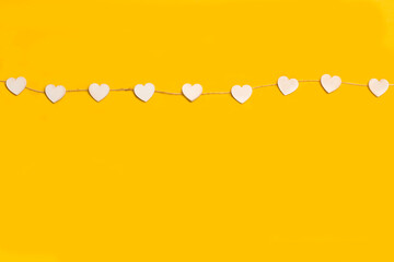 Guirnalda de corazones blancos sobre un fondo amarillo brillante liso y aislado. Vista superior y de cerca. Copy space - obrazy, fototapety, plakaty