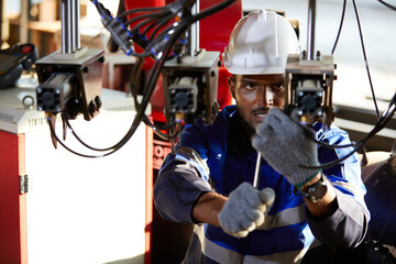African engineer or worker checking and fixing machine in robot factory