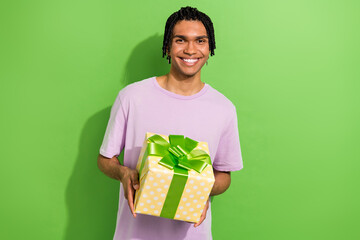 Photo of nice cheerful man toothy smile hands hold giftbox ribbon bow isolated on green color background