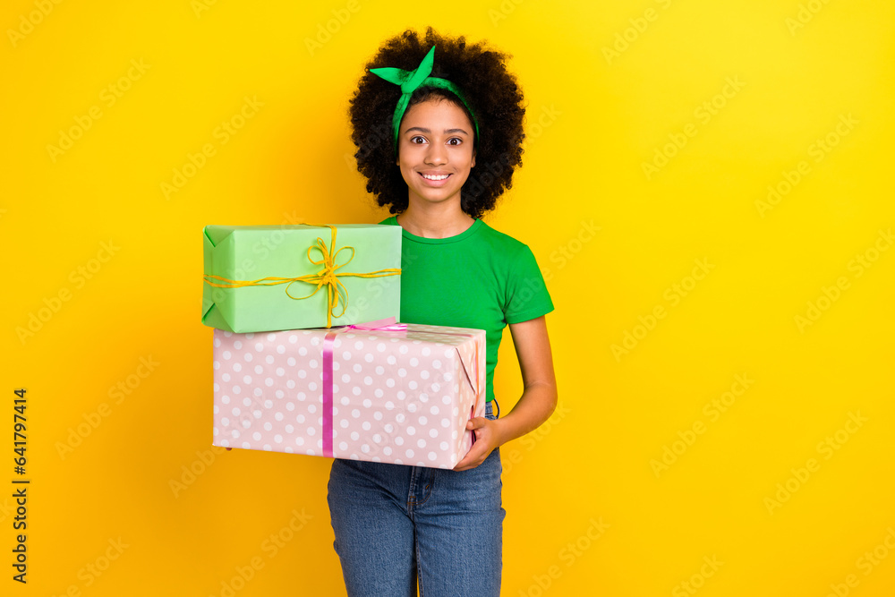 Poster portrait of cheerful adorable girl beaming smile hands hold pile stack giftbox isolated on yellow co