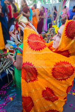 women devotee standing in river and praying with religious offerings for sun god in Chhath festival