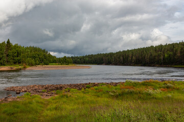 River bank with curve between mountains of pine trees in the background