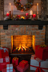 Many gift boxes near the Christmas fireplace in a festive interior of a Log Cabins with wooden walls. Mantelpiece with candles, Christmas wreath with bells