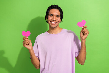 Photo of friendly attractive man toothy smile hands hold small heart shape cards isolated on green color background