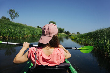 Kayaking girl background. River activity. Holiday girl in pink hat. Rowing in a canoe. Lifestyle woman vacation. Narrow river paddling.