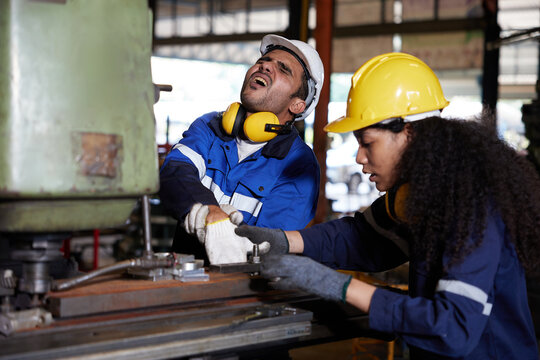 male worker or engineer have been injured in an accident from working on machine and coworker try to help him in the factory