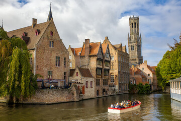 Obraz premium the Rozenhoedkaai canal in bruges with the famous belfry tower in the background and an excursion boat