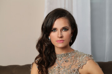 Pretty young adult woman with makeup and jewelry indoor portrait, beautiful female face closeup