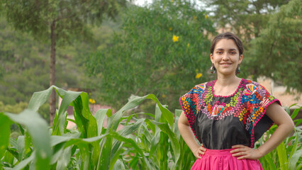 Mexican woman smiling with traditional Mexican dress standing on the corn field. Mexico concept....