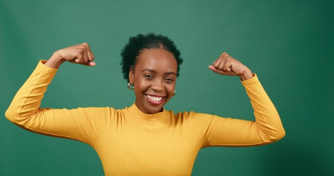 Beautiful strong woman flexes both arms, muscle, green studio background