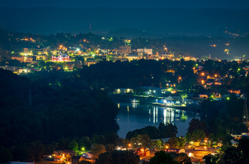 Cityscape of the city of Morgantown in West Virginia at night with lights and reflection in the river. The university campus is in the distance