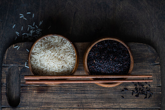 Raw wild black rice and peeled white rice in the bowls with chopsticks.