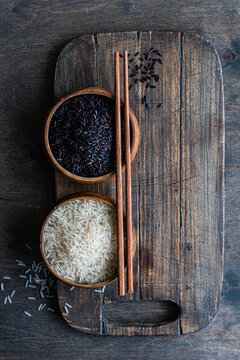 Raw wild black rice and peeled white rice in the bowls with chopsticks.