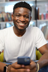 A happy young African American student, sitting in a library, enjoying education and knowledge.