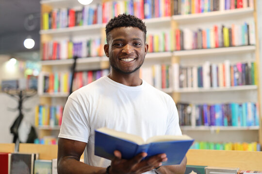 A young man immersed in learning at a library, surrounded by books and knowledge.