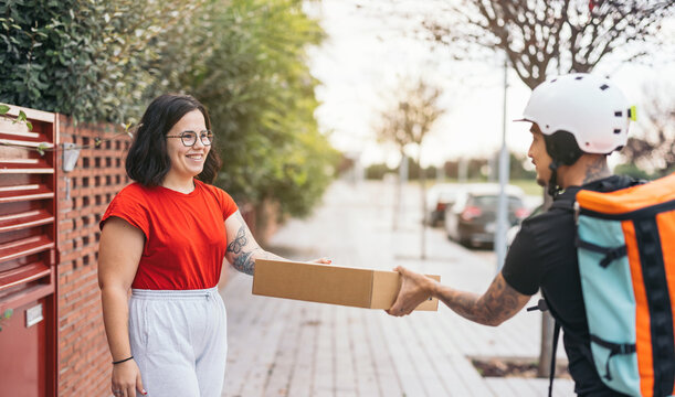 Happy customer receiving parcel from courier on sidewalk