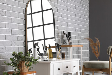 Different hairdressing tools on table near grey brick wall