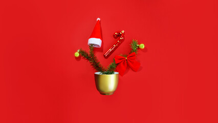 Christmas composition. Gold coffee cup with pine tree, red bow, Santa hat and ornaments on red...
