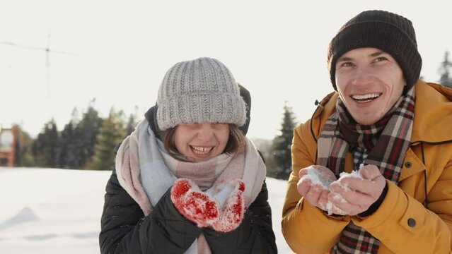 Together, they create a great mood, immersing themselves in an inspiring world of fun and romance. Winter fun in winter in the yard in nature. Hold the snow in their hands and blow it away