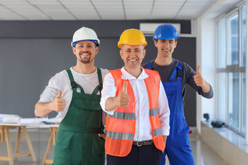 Team of male builders showing thumbs-up in room