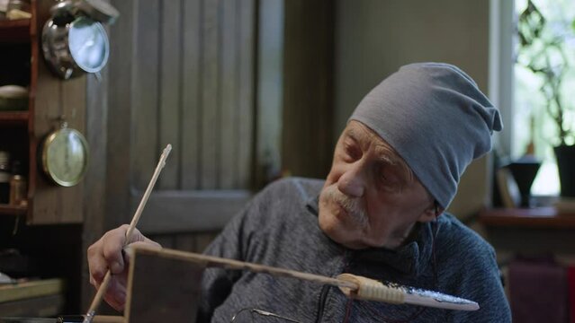 Elderly male master works in his workshop restoring japanese deba knife sheath