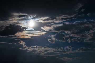 Fototapeta na wymiar Beautiful clouds brightly lit by moonlight in the night sky
