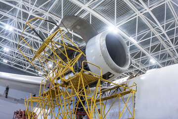 Open high-bypass turbofan aircraft engine of a transport airplane in a hangar