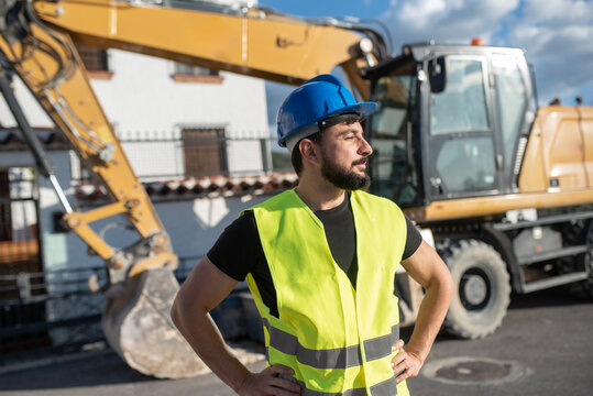 construction worker near to backhoe looking at camera smiling
