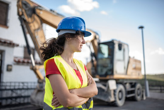 Female construction worker near to backhoe
