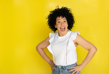 Cuban young woman with afro hair laughing. Outdoors yellow background