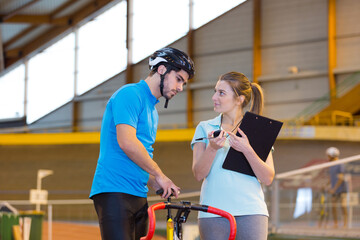 Fototapeta na wymiar trainer woman talking with a man doing exercise bike
