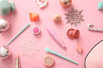 Makeup products and Christmas decorations on pink background