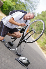 Fototapeta premium mature man repairing bicycle outdoors on tarmac surface