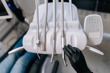 Close-up top view of unrecognizable dentist in rubber gloves taking electrical dental drill from...