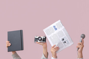 Female hands with newspaper, notebook, microphone and photo camera on color background