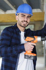 happy worker drilling a hole in the wall