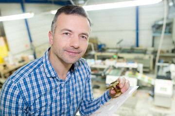 Obraz premium worker holding bolts and coil in a factory