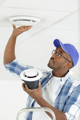man installing ventilation grill in ceiling