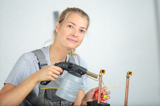 female jeweller blowing a torch - Powered by Adobe
