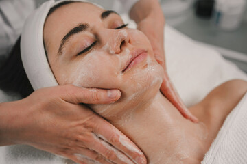Young pretty woman receiving treatments using facial cleansing foam in beauty salons. Body massage...
