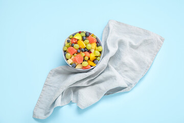 Bowl with fresh fruit salad on blue background