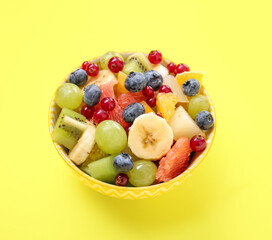 Bowl with fresh fruit salad on yellow background
