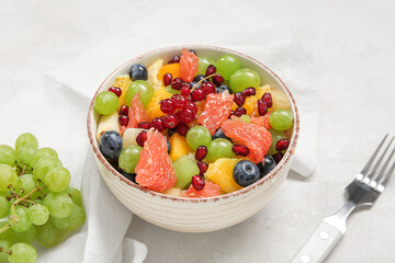 Bowl of fresh fruit salad on light background