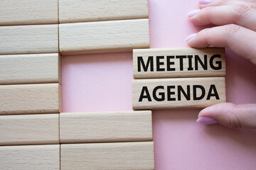 Meeting agenda symbol. Concept word Meeting agenda on wooden blocks. Businessman hand. Beautiful pink background. Business and Meeting agenda concept. Copy space