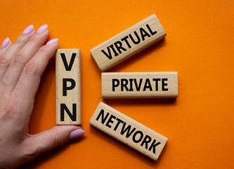 VPN - Virtual Private Network. Wooden cubes with word VPN. Businessman hand. Beautiful orange background. Business and VPN concept. Copy space.